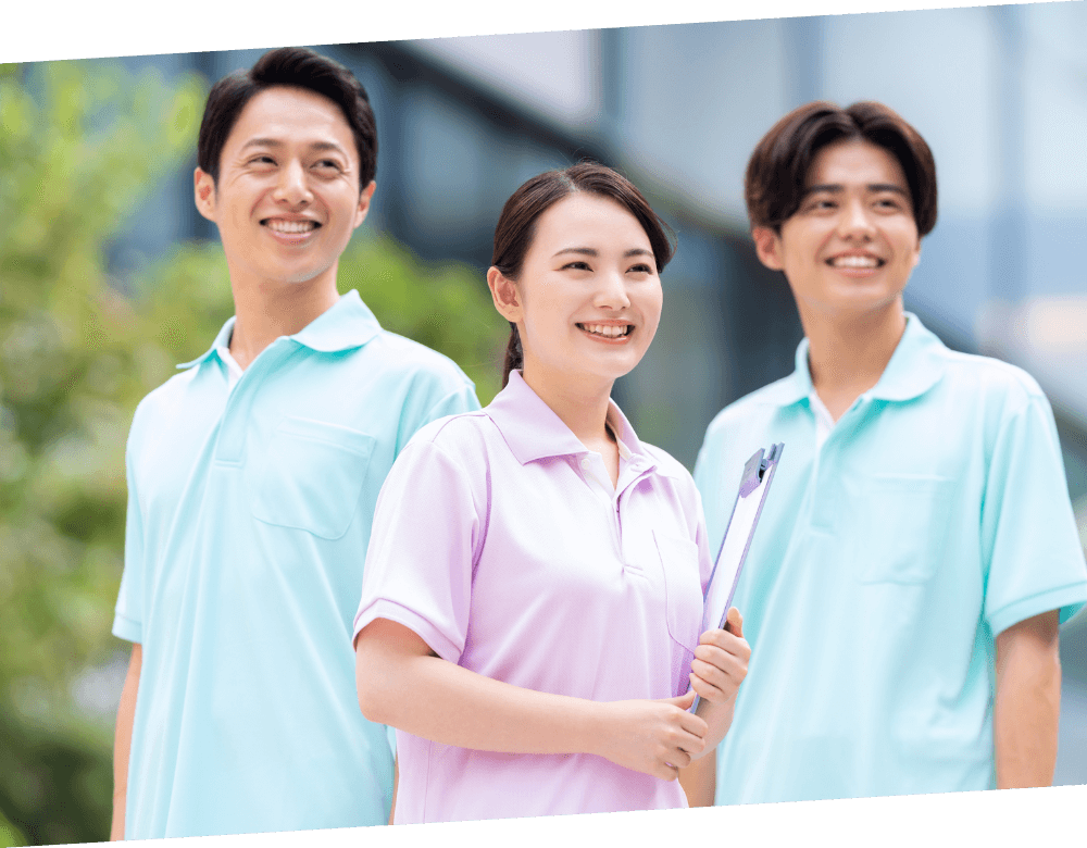 笑顔の若い介護士たちが屋外で並んで立っている様子